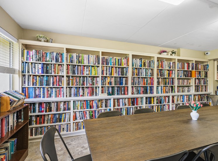 entire wall full of book shelves with books and reading table in library